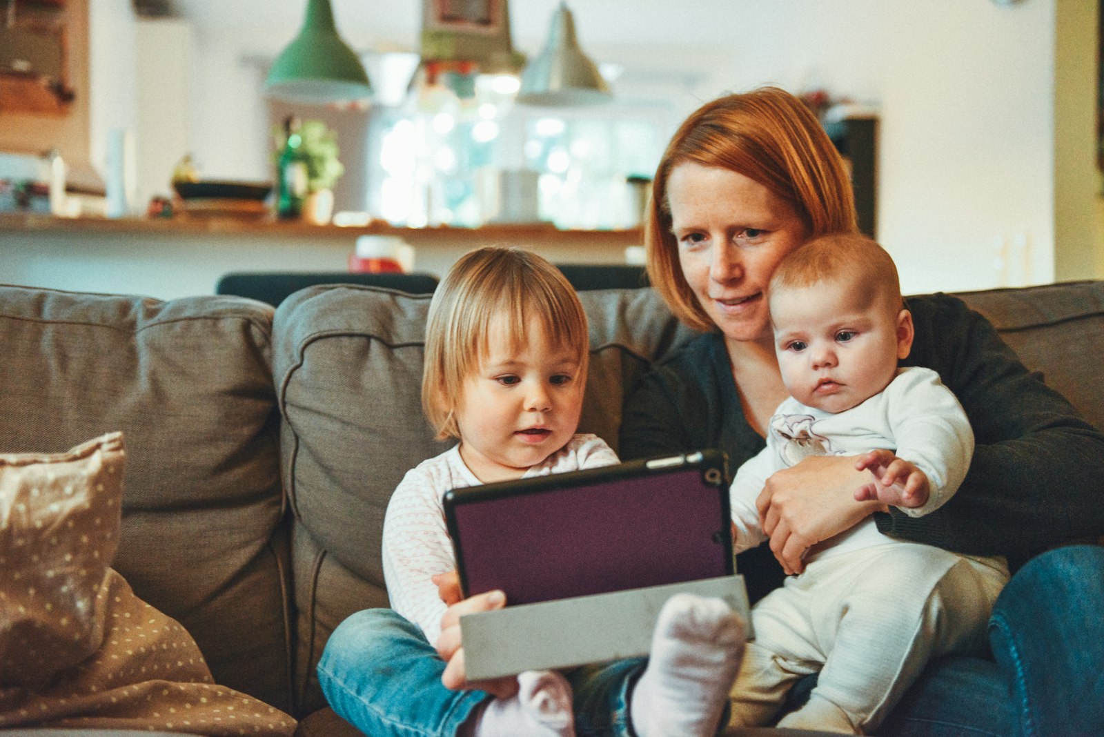Madre con sus dos hijos en el sofá de casa